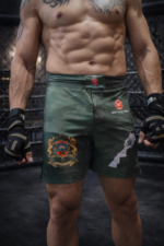 Short MMA Moroccan Punch camouflage vert avec emblème marocain et carte du Maroc, porté par un combattant dans une cage MMA, idéal pour Jiu Jitsu, Muay Thai, CrossFit et sports de combat.